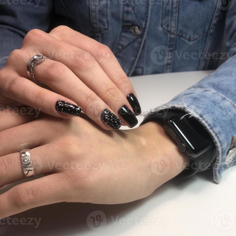 manicure feminina preta na moda elegante. mãos de uma mulher com manicure preta nas unhas foto