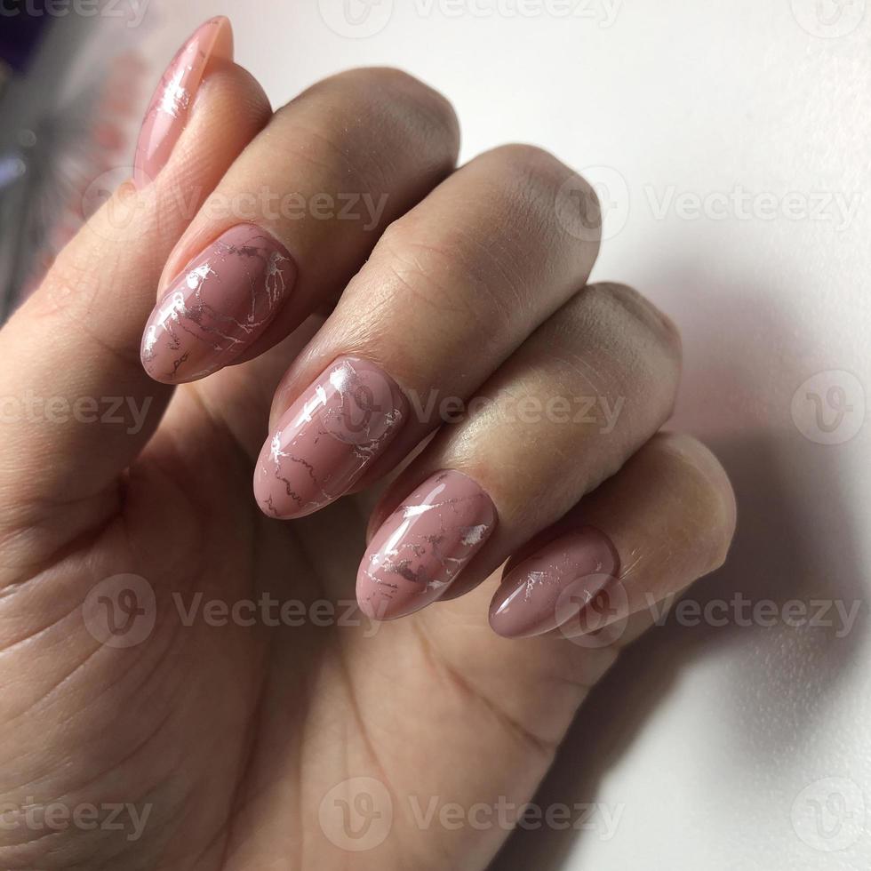 manicure rosa feminina na moda elegante. mãos de uma mulher com manicure rosa nas unhas foto