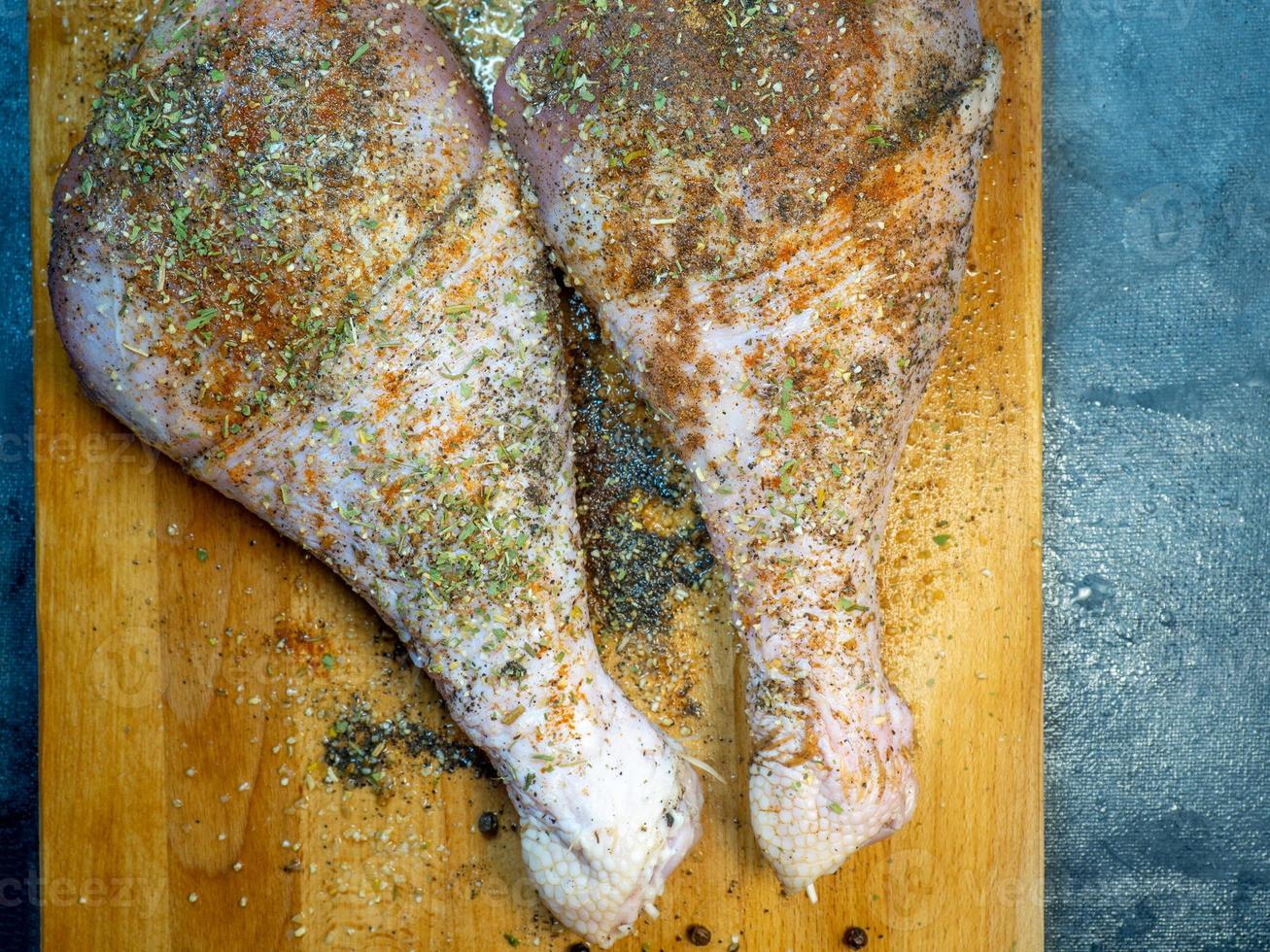 coxinhas de peru em especiarias estão em uma tábua de cozinha. carne de aves. coxa de peru. carne suculenta está esperando para ser cozida. esperando o forno. foto