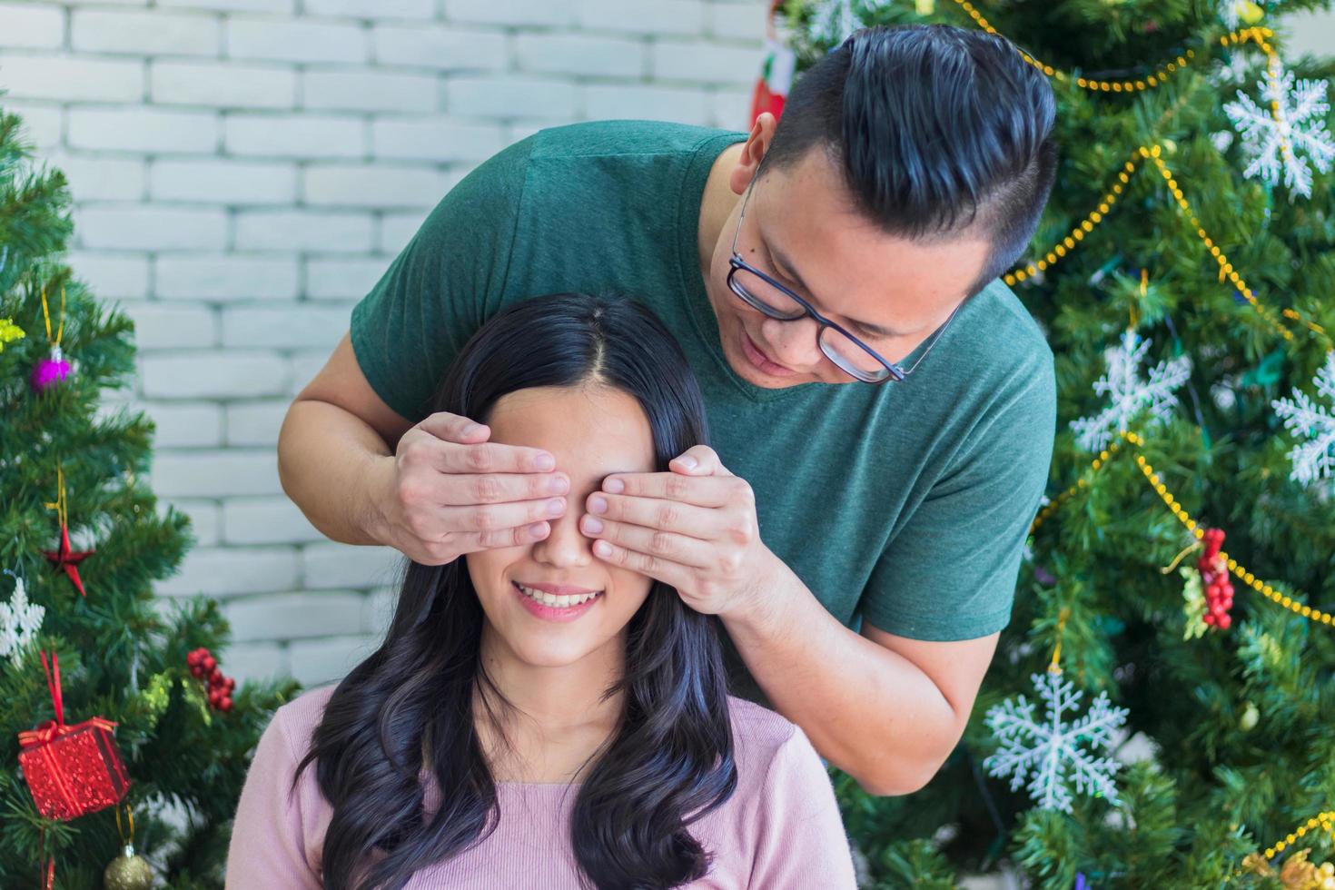 homem surpreendente mulher com árvores de natal no fundo foto