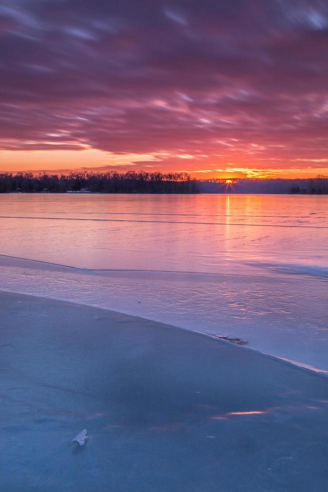 pôr do sol de inverno colorido sobre um lago congelado foto