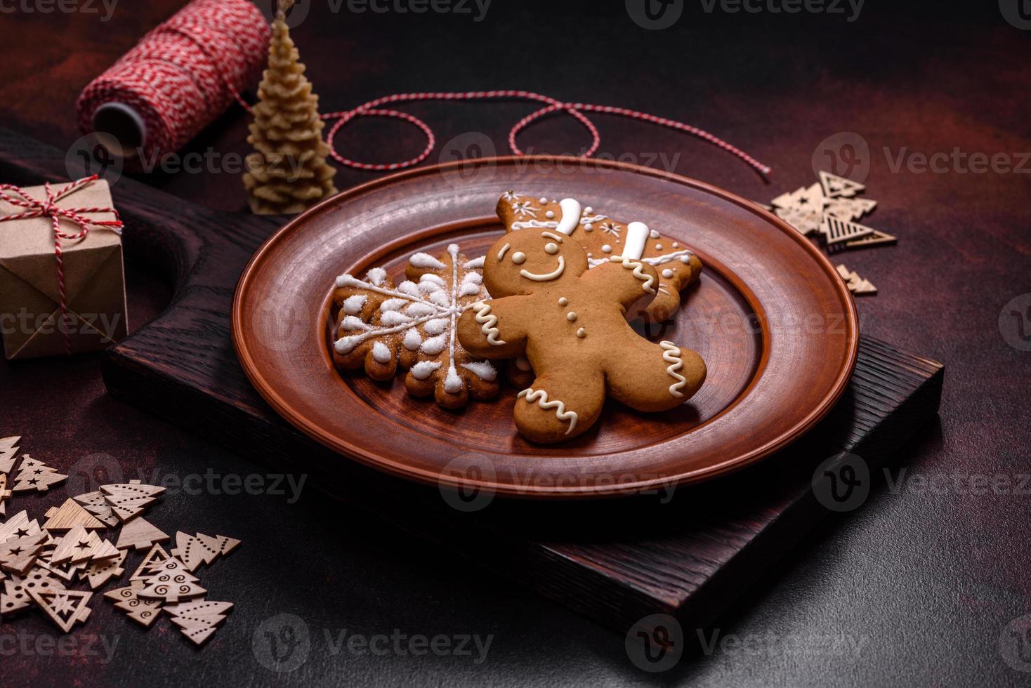 lindo pão de gengibre em um prato de cerâmica marrom com enfeites de árvore de natal em um fundo escuro de concreto foto