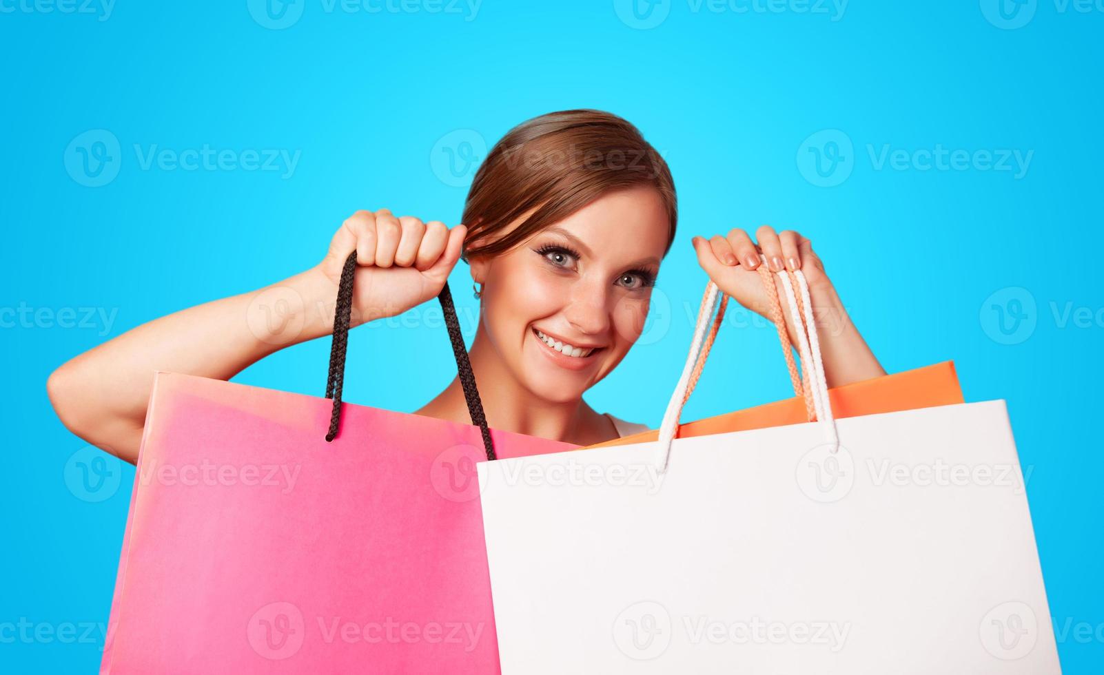 menina morena com sacolas de compras em backgorund azul. foto