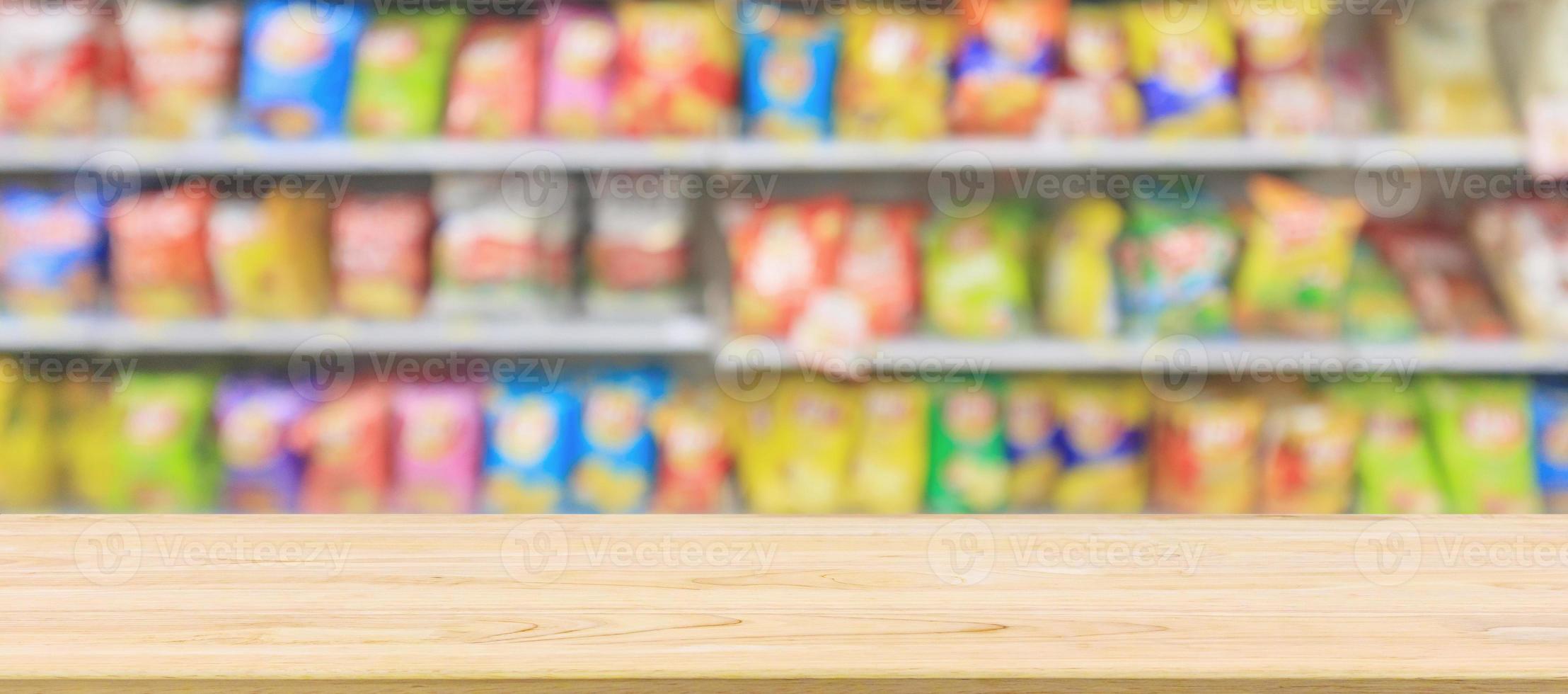 tampo da mesa de madeira com prateleiras de loja de conveniência de supermercado com batatas fritas lanche borrão abstrato foto
