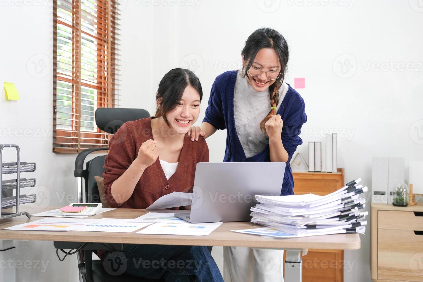 duas mulheres asiáticas comemorando a vitória, ganhou um contrato lucrativo, uma vitória surpreendente inesperada, grande coisa em estoque, conquista impressionante, sucesso inacreditável, emoções positivas engraçadas em casa foto