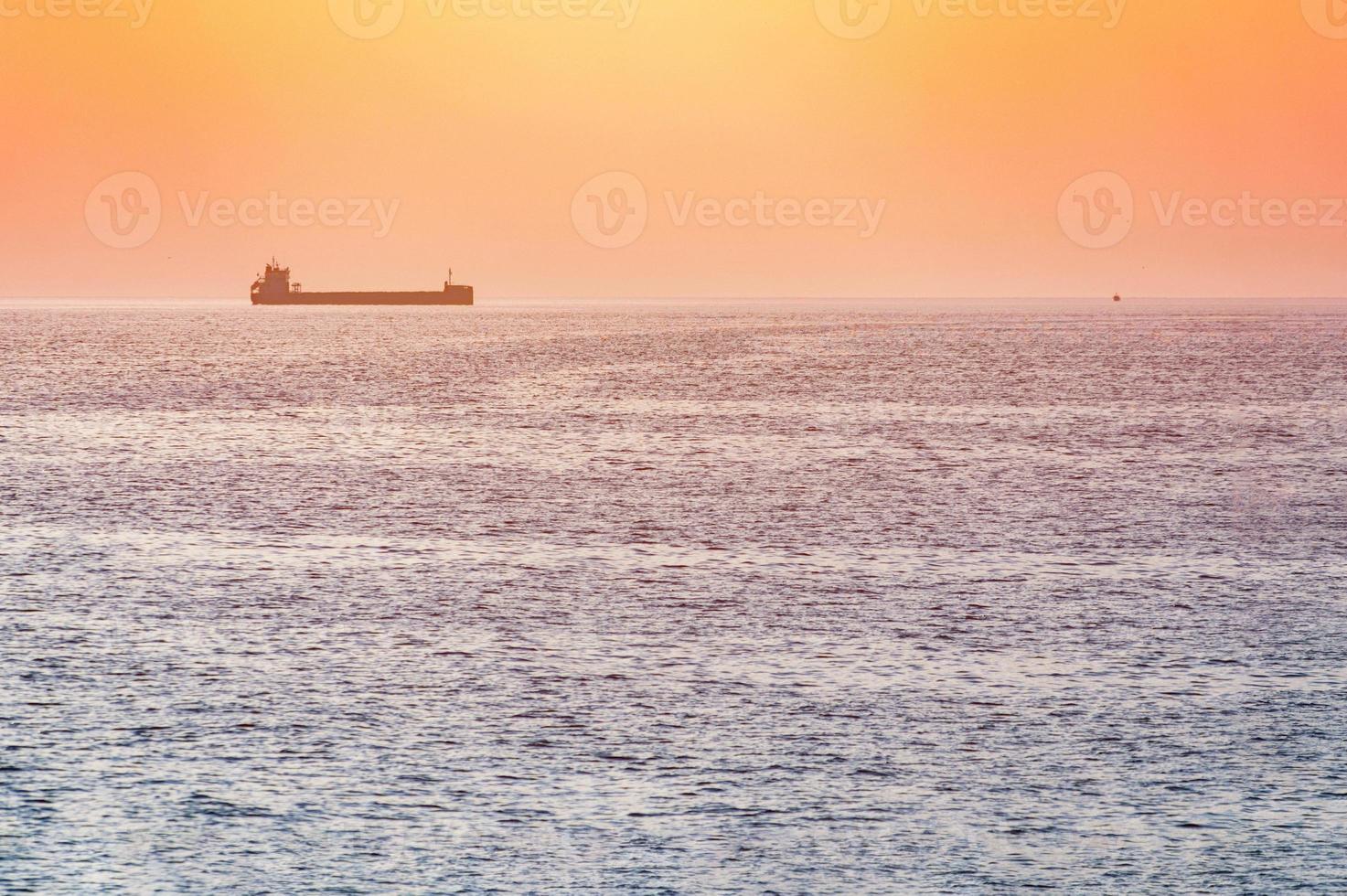 pequeno rebocador e grande cargueiro. belo pôr do sol sobre o mar. vista de viagem de tirar o fôlego, copie o espaço. foto