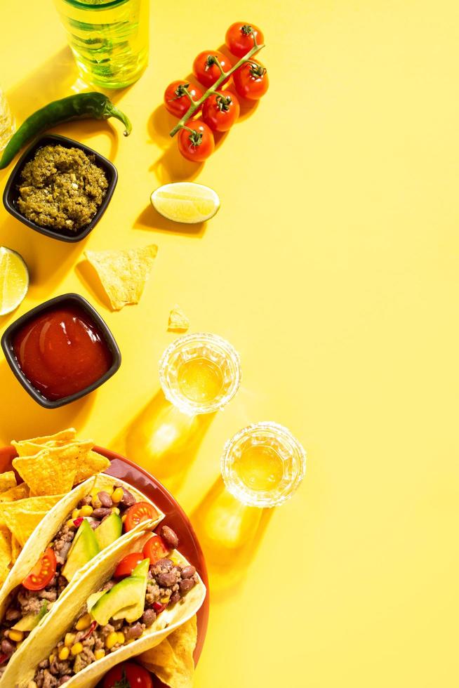 shots de tequila mexicana com limão e pimenta vermelha quente com tacos de milho de comida tradicional no fundo foto