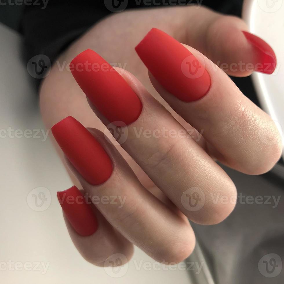 manicure feminino vermelho fosco na moda elegante. mãos de uma mulher com manicure vermelho nas unhas foto