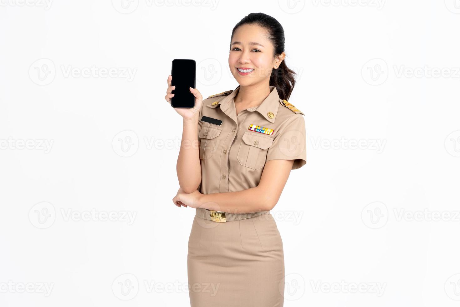 retrato de sorridente jovem professora asiática apresentando no telefone em pé sobre fundo branco. foto