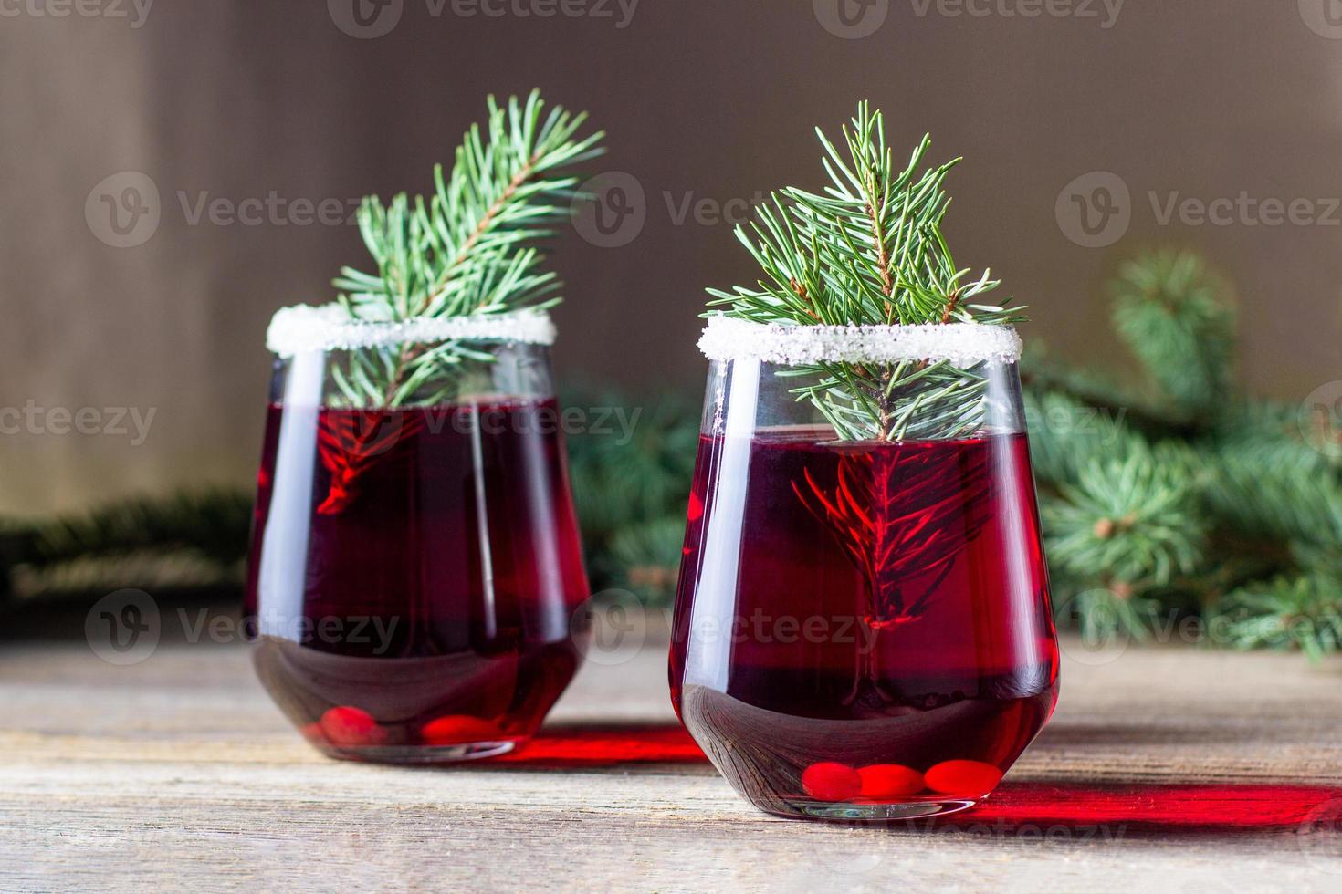 bebida vermelha de cranberry decorada com bagas de galhos de árvores de abeto e açúcar. vinho quente de natal foto