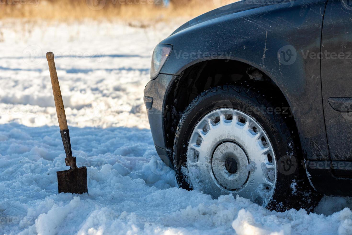 carro preso na neve offroad à luz do dia com pá e foco seletivo foto