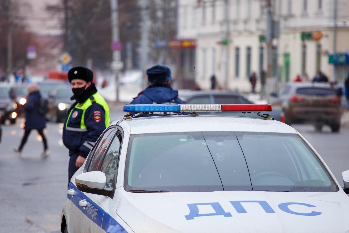 tula, rússia, 23 de janeiro de 2021, policiais rodoviários russos em pé perto do carro de patrulha na estrada de inverno - close-up com foco seletivo na lâmpada do telhado. foto