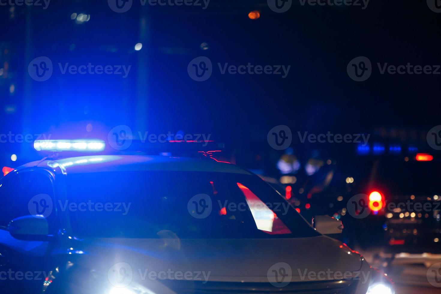 carro de polícia de estrada irreconhecível com luz de sirene vermelha e azul acesa em seu telhado na estrada da cidade à noite foto