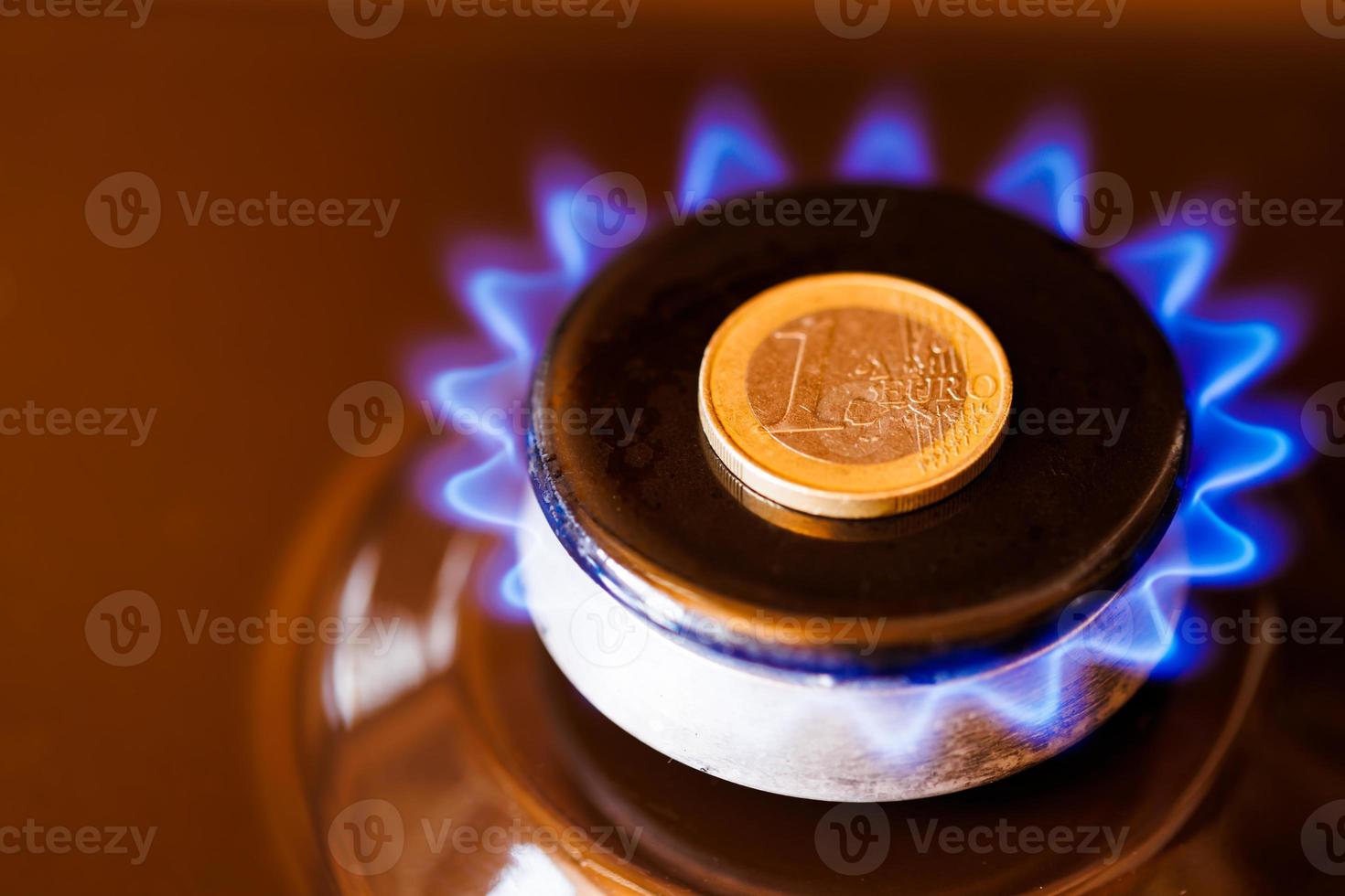 queimador de fogão a gás com uma moeda de euro colocada em cima, queimando gás natural com chama azul foto