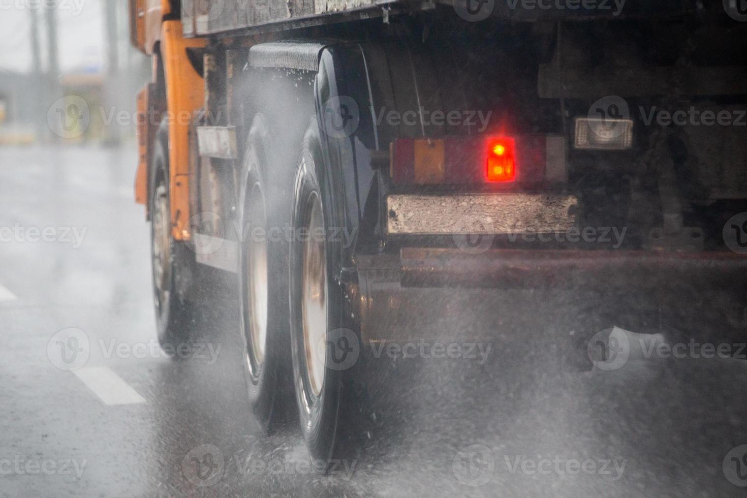 fluxo de respingos de água da chuva das rodas do caminhão pesado se movendo rapidamente na cidade da luz do dia com foco seletivo. foto