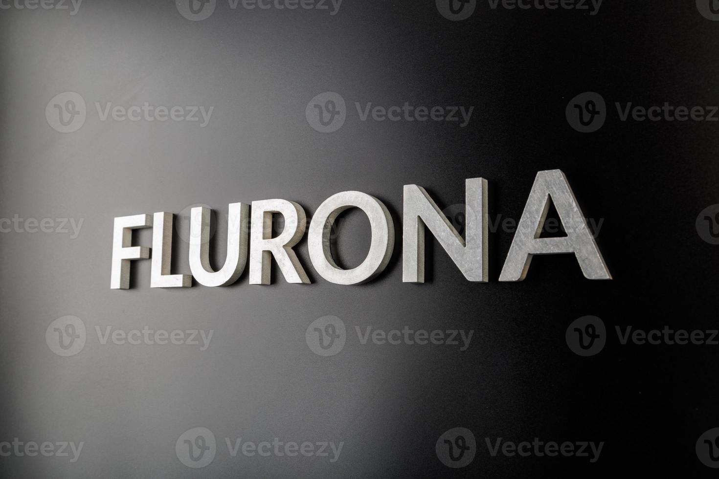 a palavra flurona colocada com letras de metal prateado em fundo preto brilhante foto