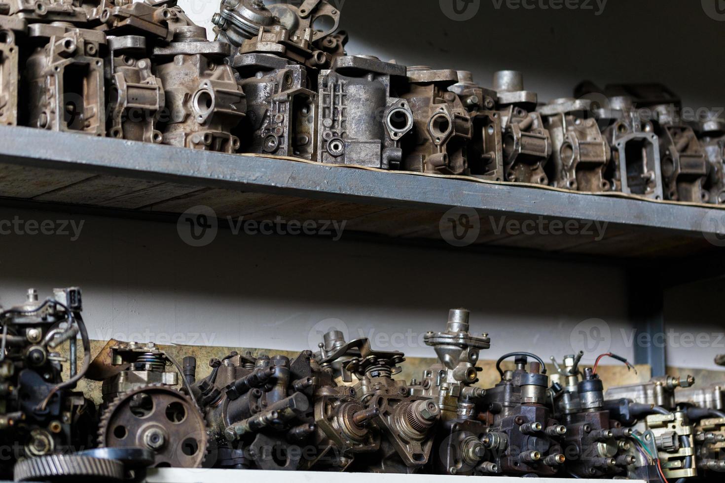 velhas peças de motor de metal sujo na prateleira de garagem escura foto
