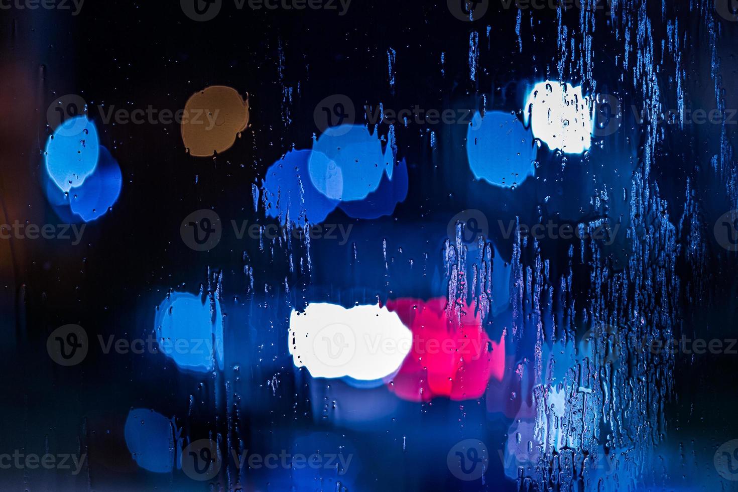 um fundo abstrato de luzes policiais vermelhas e azuis bokeh através de vidro molhado à noite close-up com foco seletivo foto