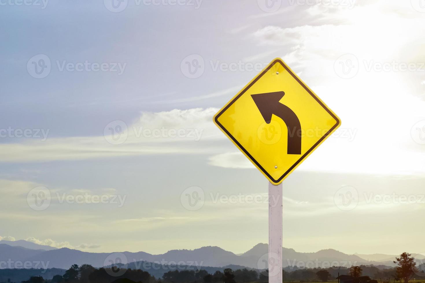 sinal de aviso de tráfego no poste, curva à esquerda significa que o caminho à frente é uma curva à direita e deve dirigir devagar e dirigir com cuidado. foto