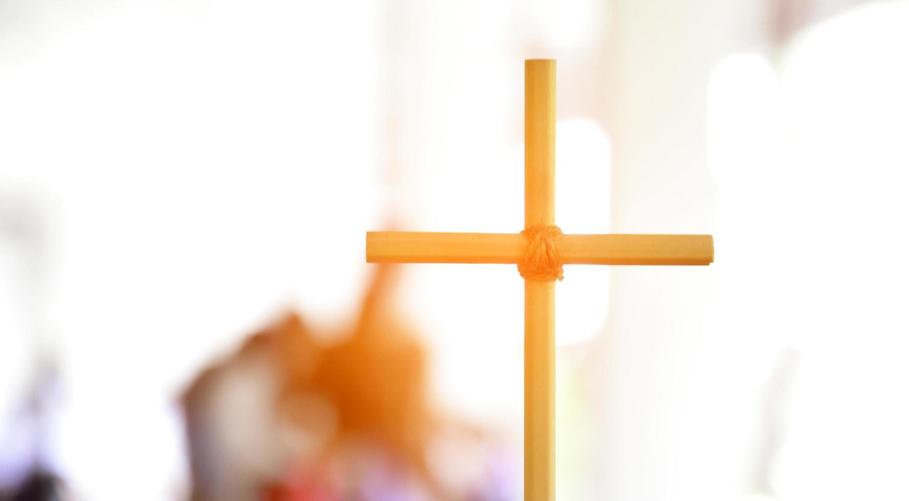 pequena cruz de madeira segurando na mão com fundo de céu nublado e azul, conceito de amor, esperança, verdade, fé, acredite em jesus, foco suave e seletivo. foto