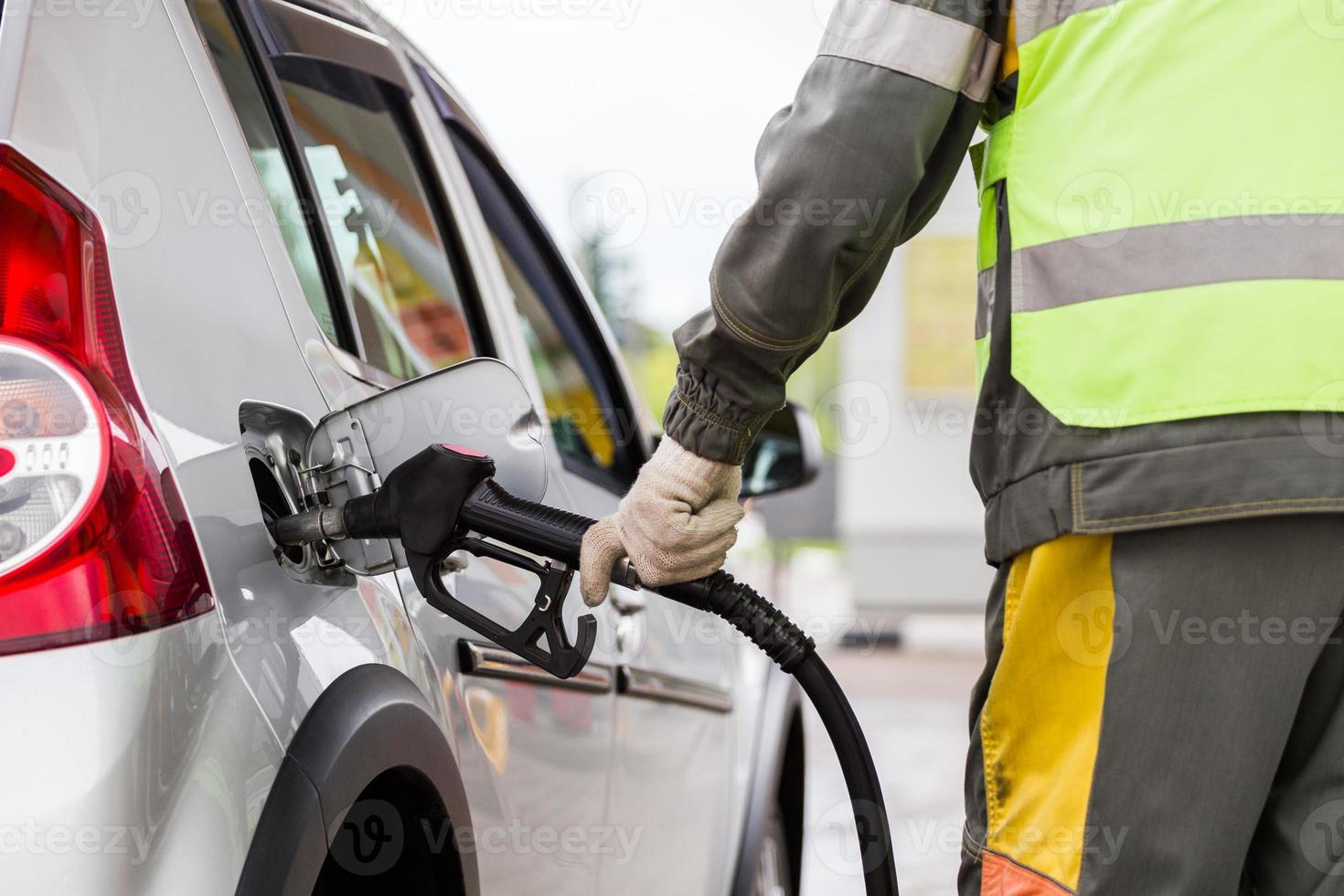 mão na luva de tecido de algodão branco reabastecimento de carro metálico cinza no posto de gasolina - close-up com foco seletivo foto