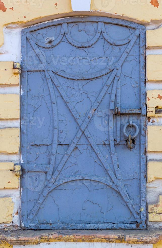 velha porta de ferro forjado com rebites e pintura azul descascada foto