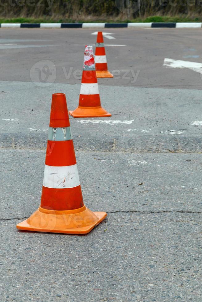 cones de trânsito laranja na superfície da estrada de asfalto cinza seco - close-up com foco seletivo foto