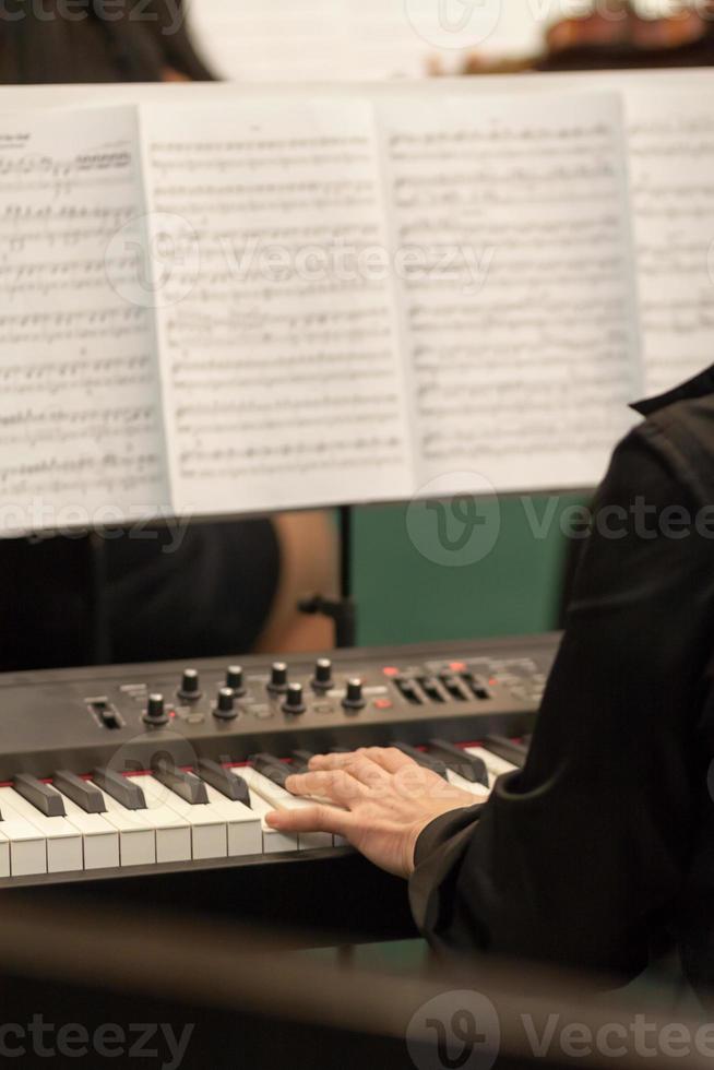 músico tocando no sintetizador musical com notas de música de papel no fundo desfocado foto