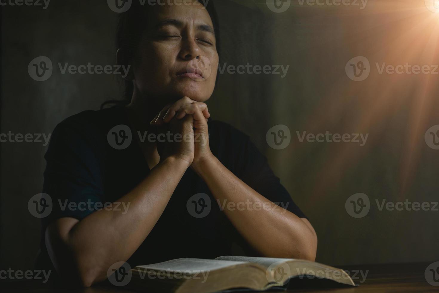 pessoa de oração mão em fundo preto. mulher católica cristã está orando a Deus no escuro na igreja. menina acreditar e fé em jesus cristo. religião de cristo e cristianismo adoram ou rezam o conceito. foto