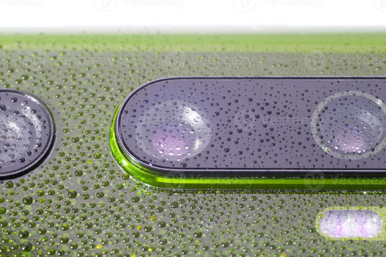 lente de câmera de telefone verde coberta com pequenas gotas de água - close-up com foco seletivo e desfoque foto