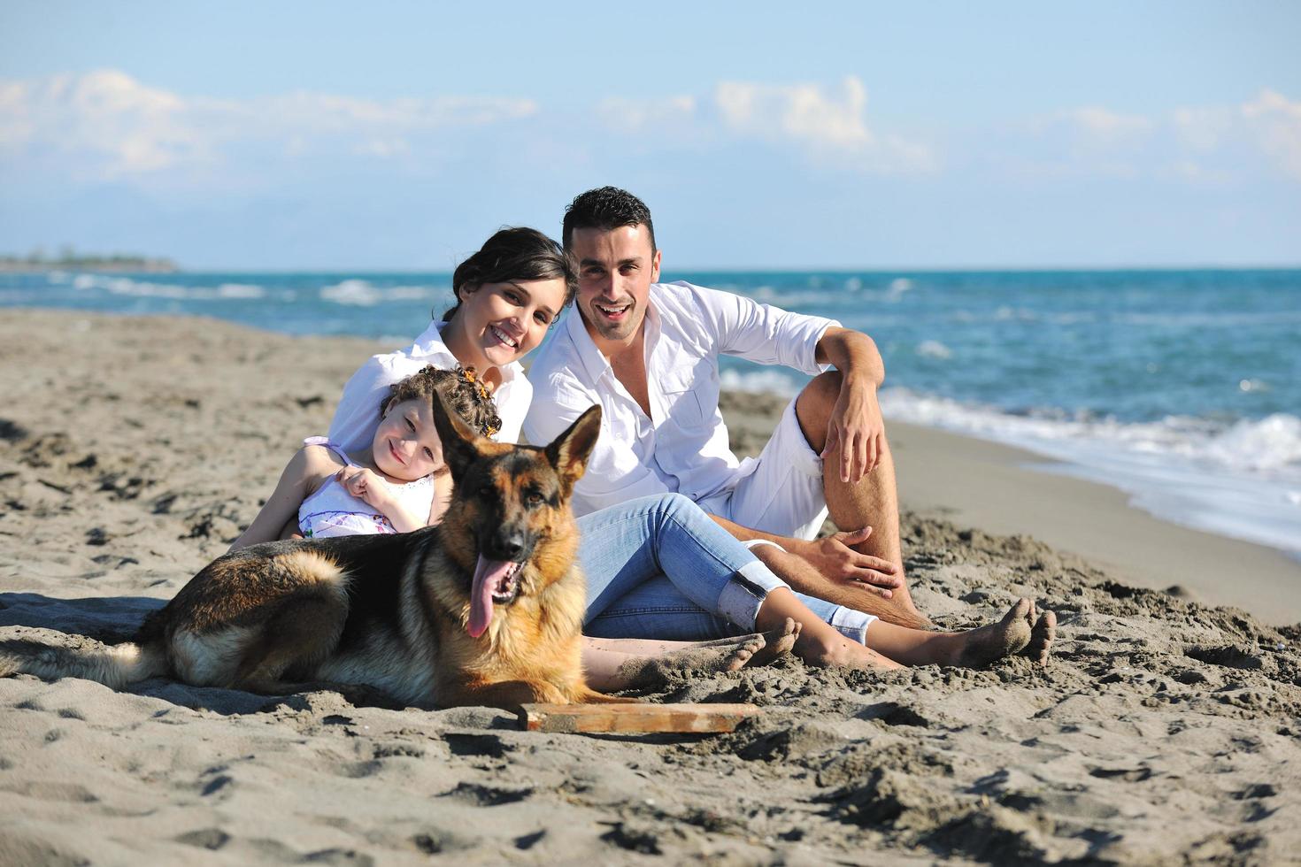 família feliz brincando com cachorro na praia foto