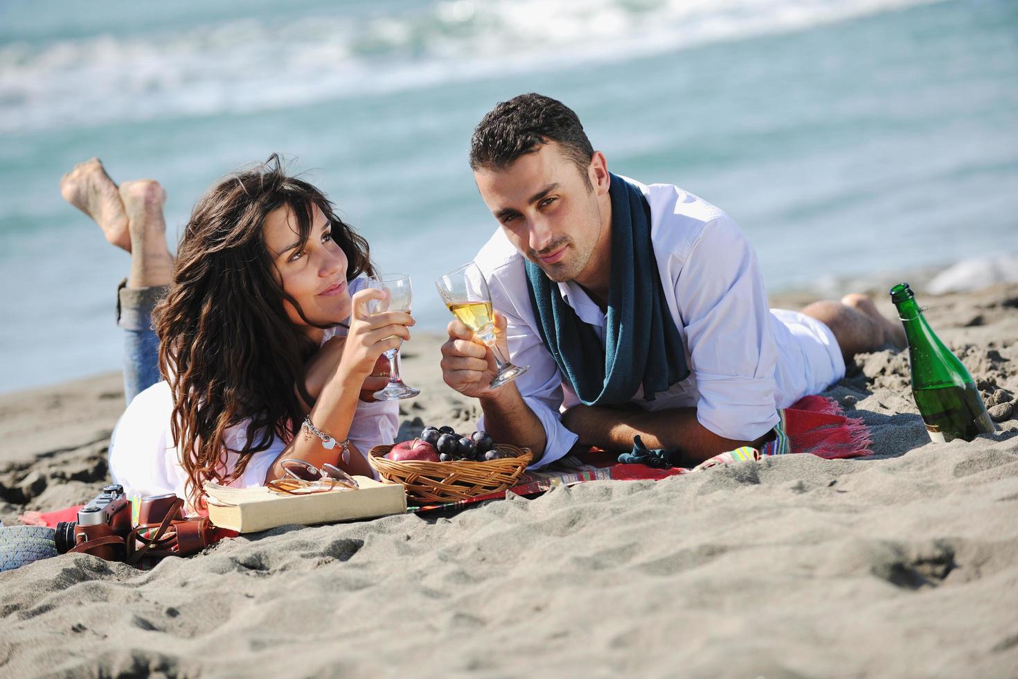 jovem casal desfrutando de piquenique na praia foto