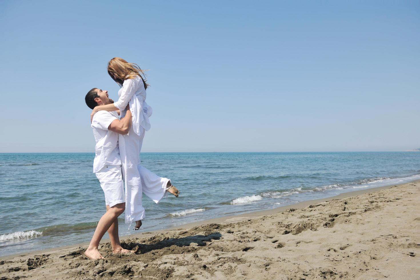 feliz casal jovem se divertir na praia foto