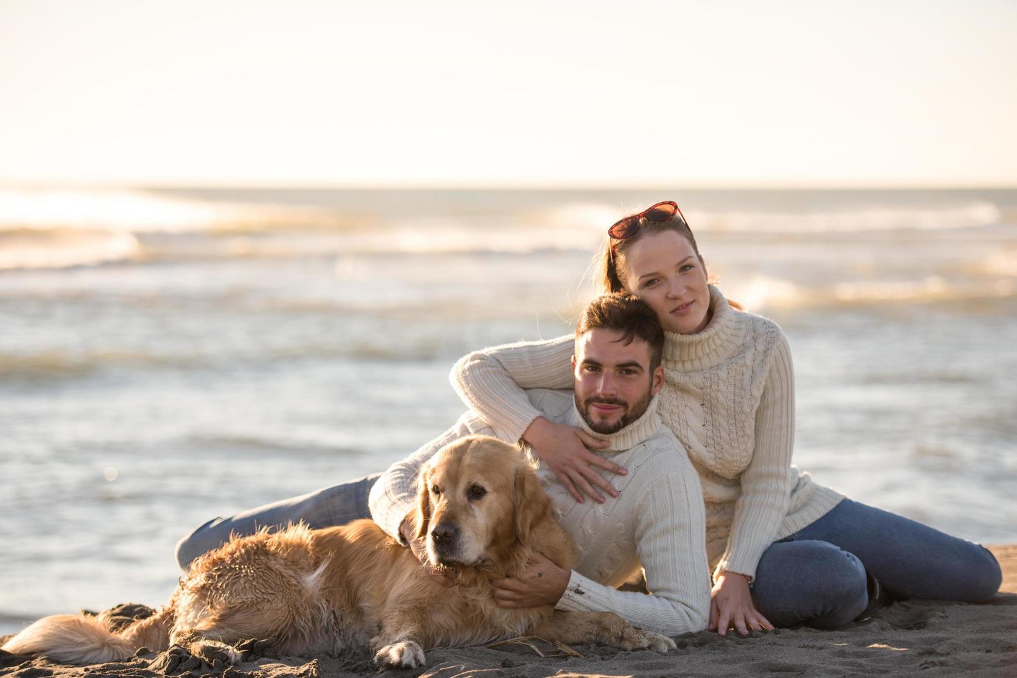 casal com cachorro aproveitando o tempo na praia foto