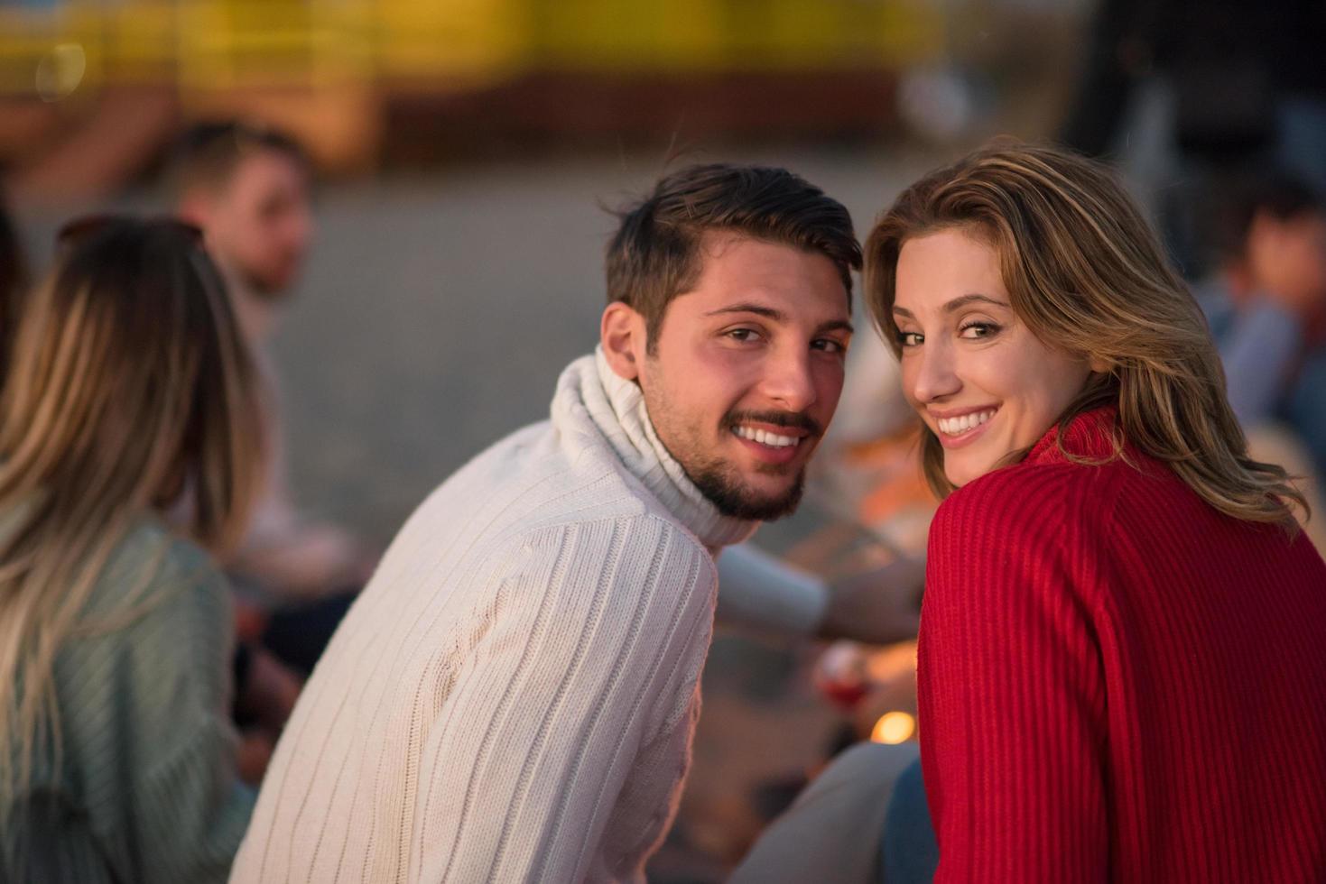 casal curtindo com amigos ao pôr do sol na praia foto