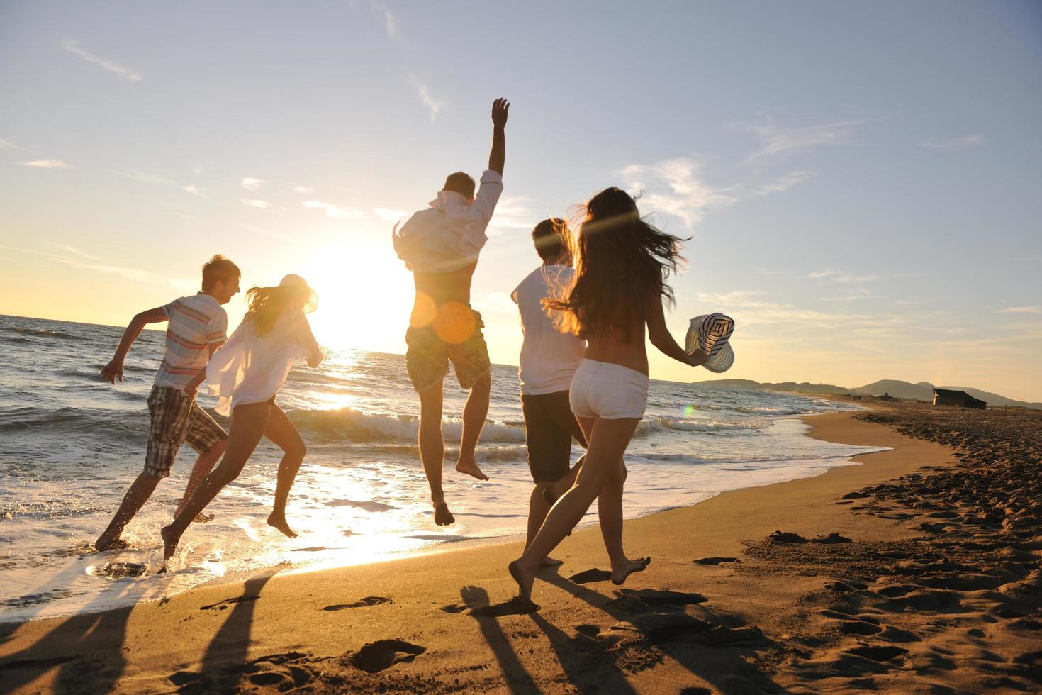 grupo de pessoas correndo na praia foto