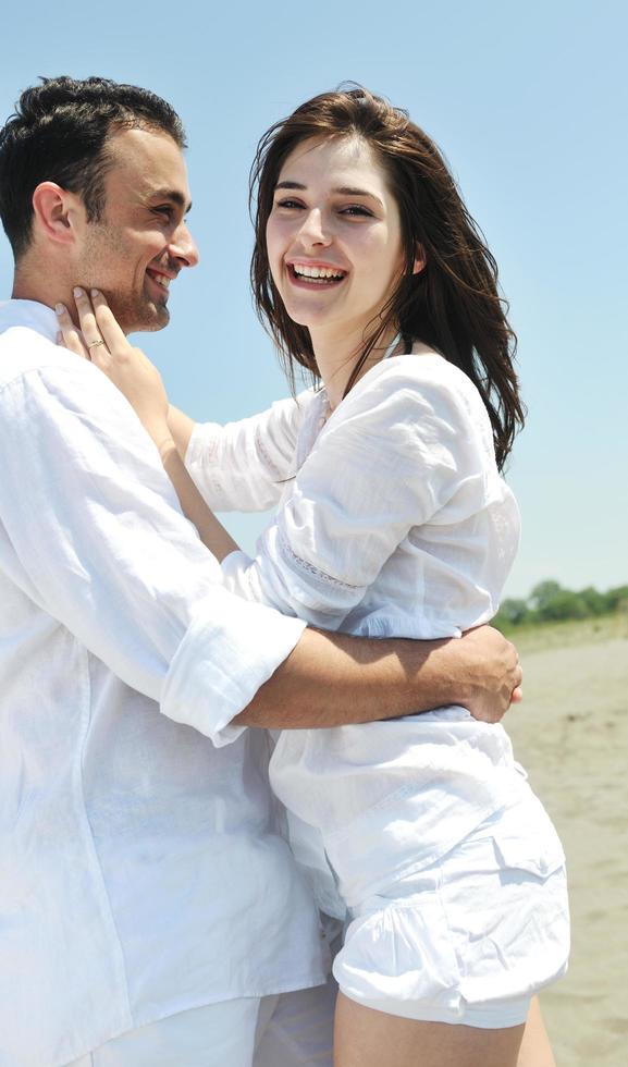 feliz casal jovem se divertir na praia foto