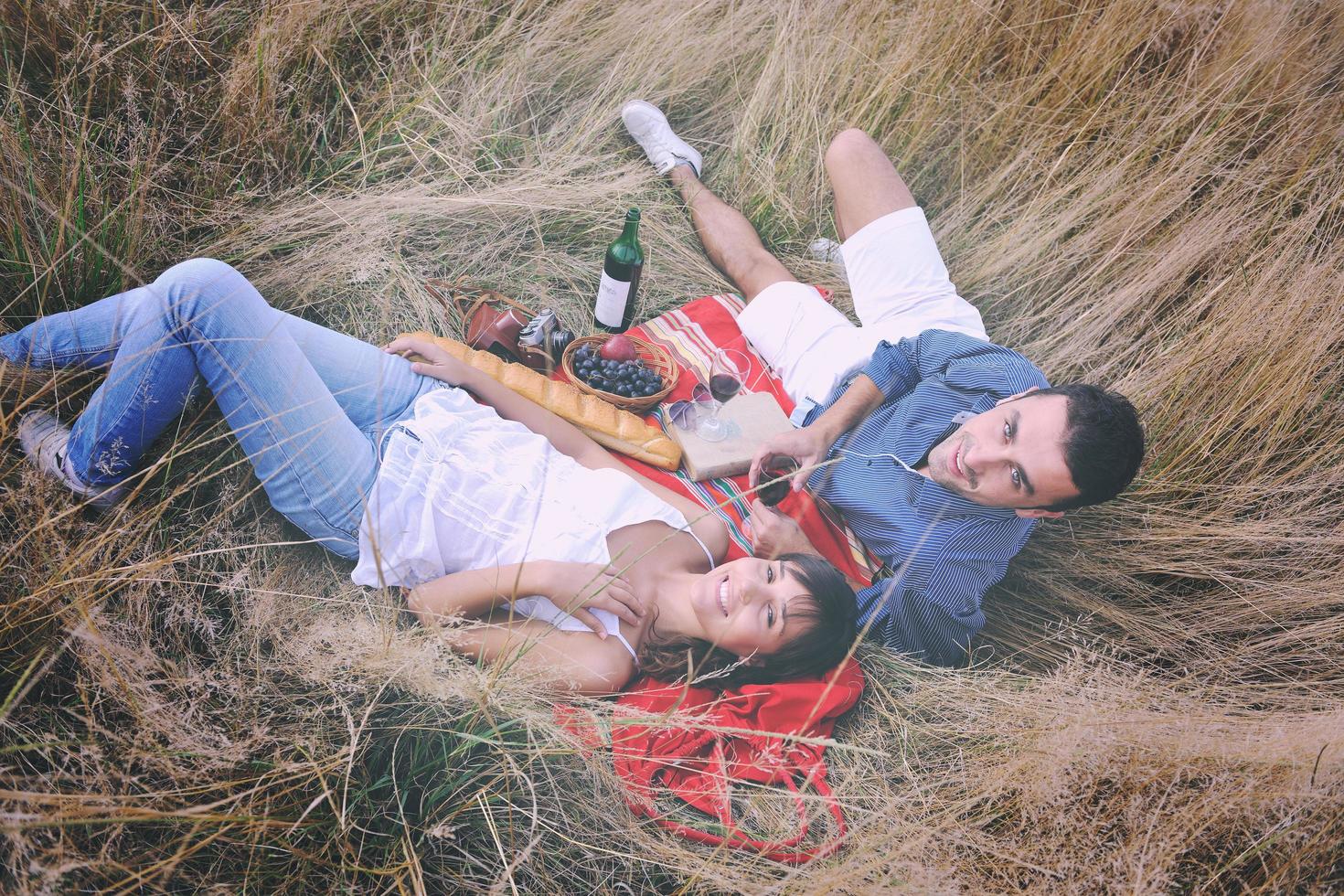 casal feliz desfrutando de piquenique no campo em grama longa foto