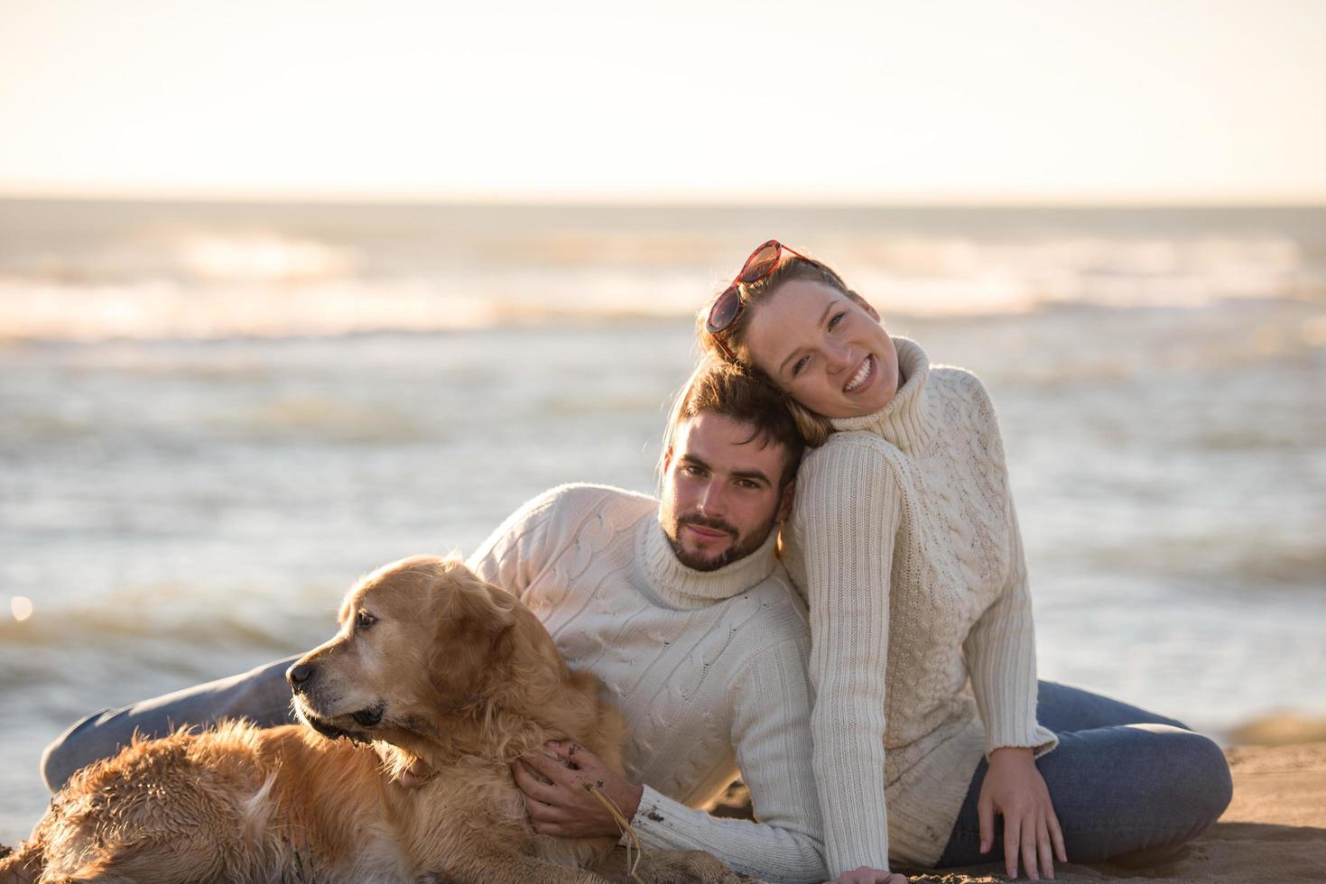 casal com cachorro aproveitando o tempo na praia foto