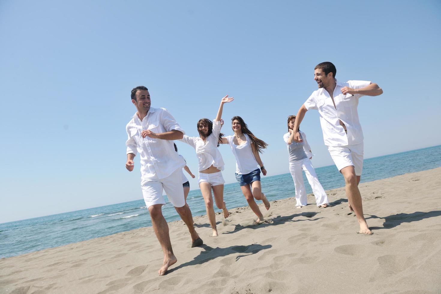 grupo de pessoas felizes se divertir e correr na praia foto