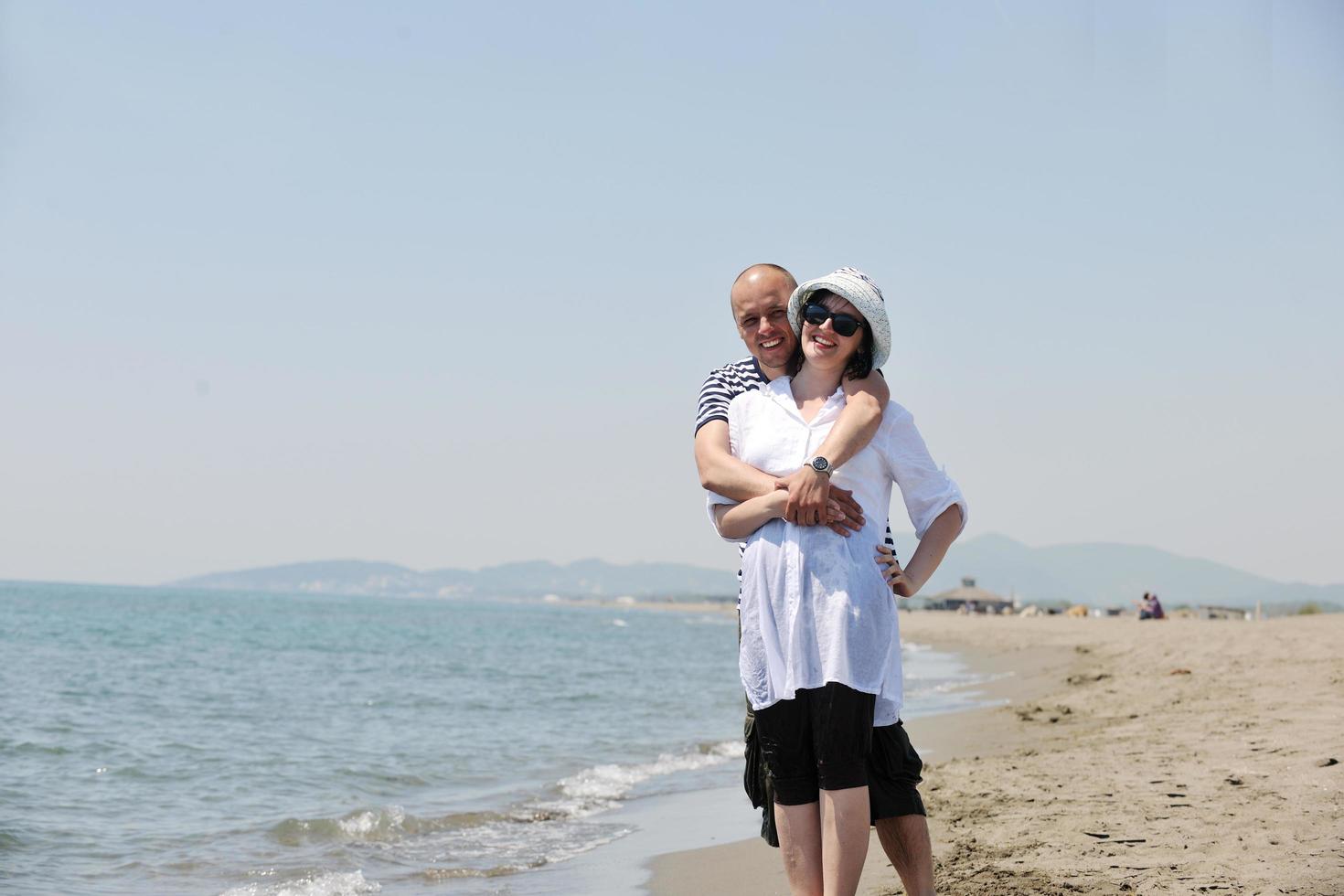 feliz casal jovem se divertir na praia foto