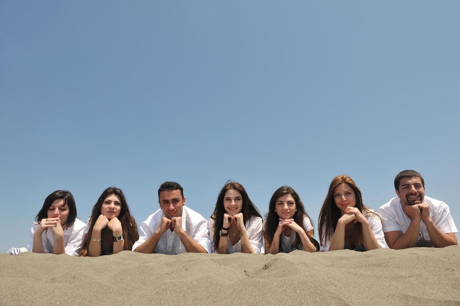 grupo de jovens felizes em se divertir na praia foto