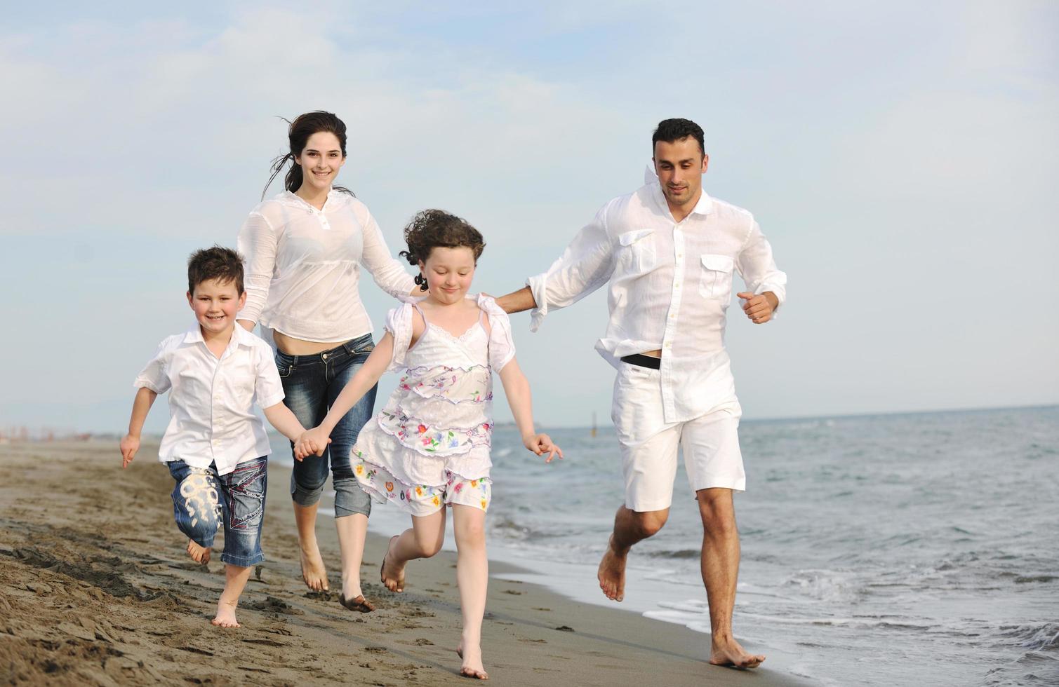 feliz jovem família se divertir na praia foto