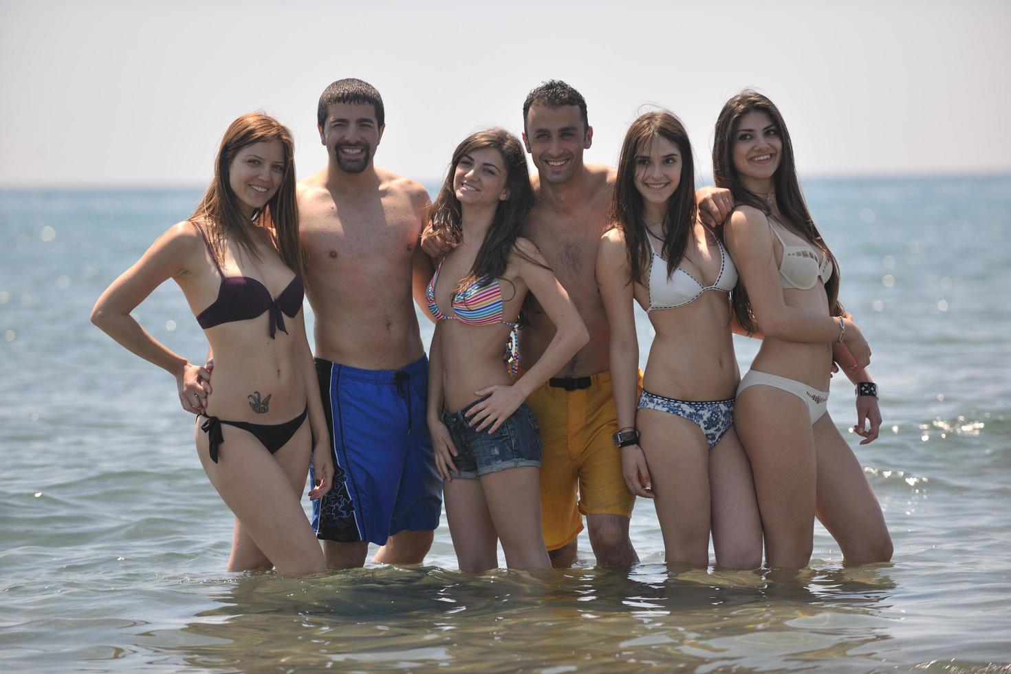 grupo de pessoas felizes se divertir e correr na praia foto