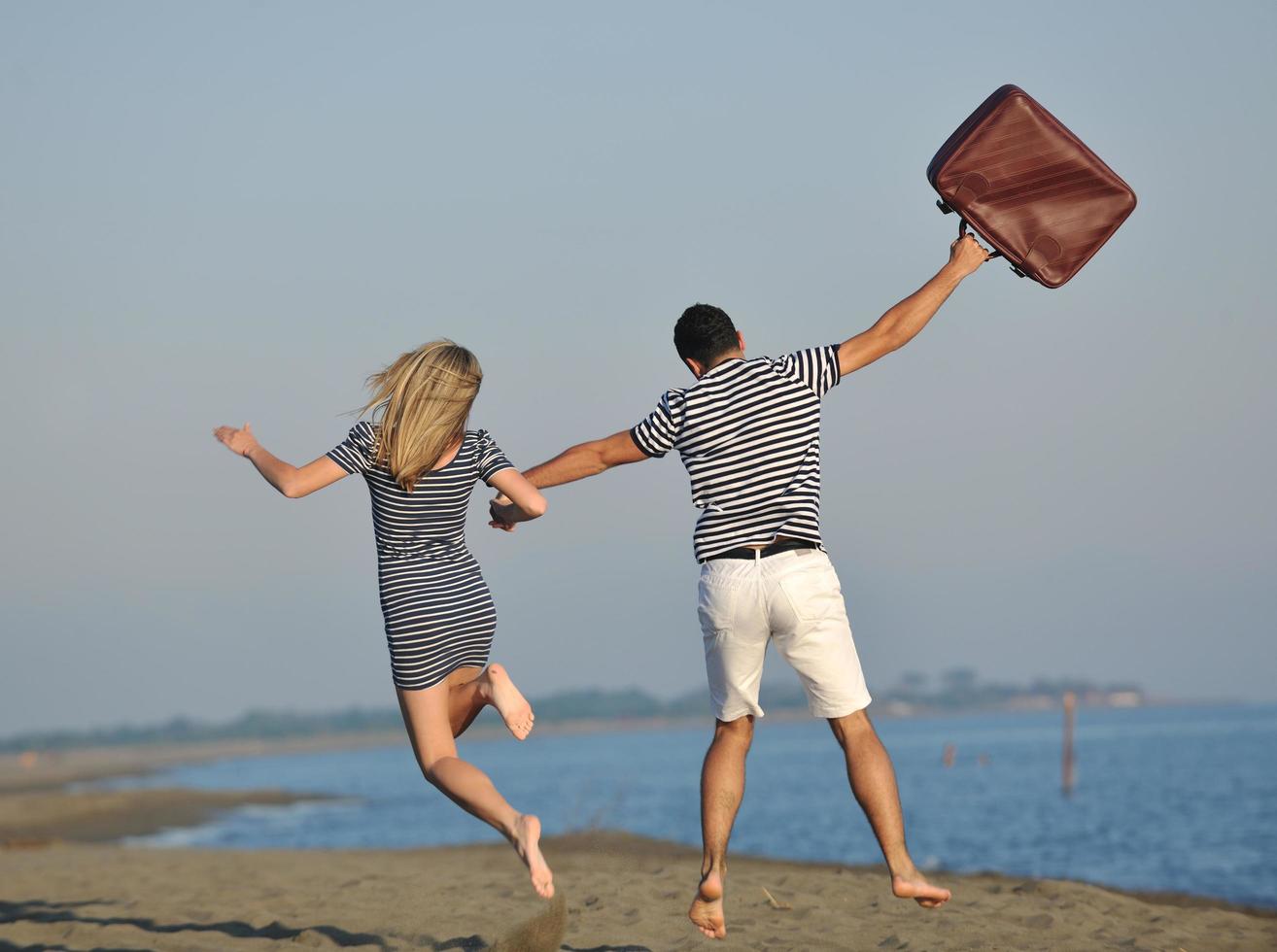 casal na praia com mala de viagem foto
