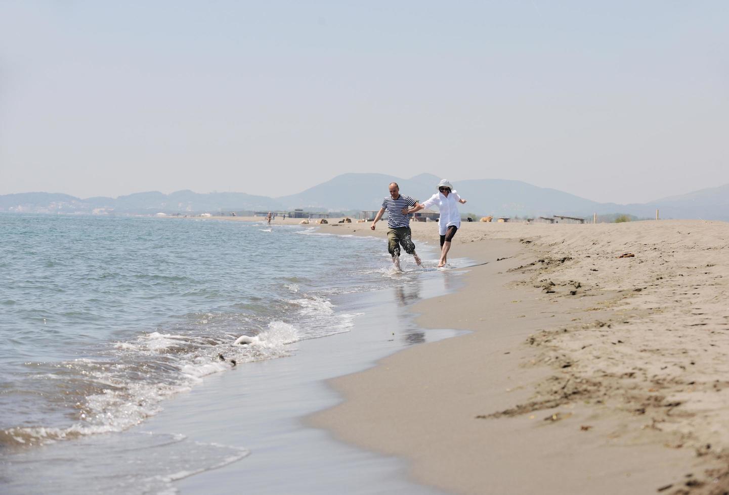 feliz casal jovem se divertir na praia foto