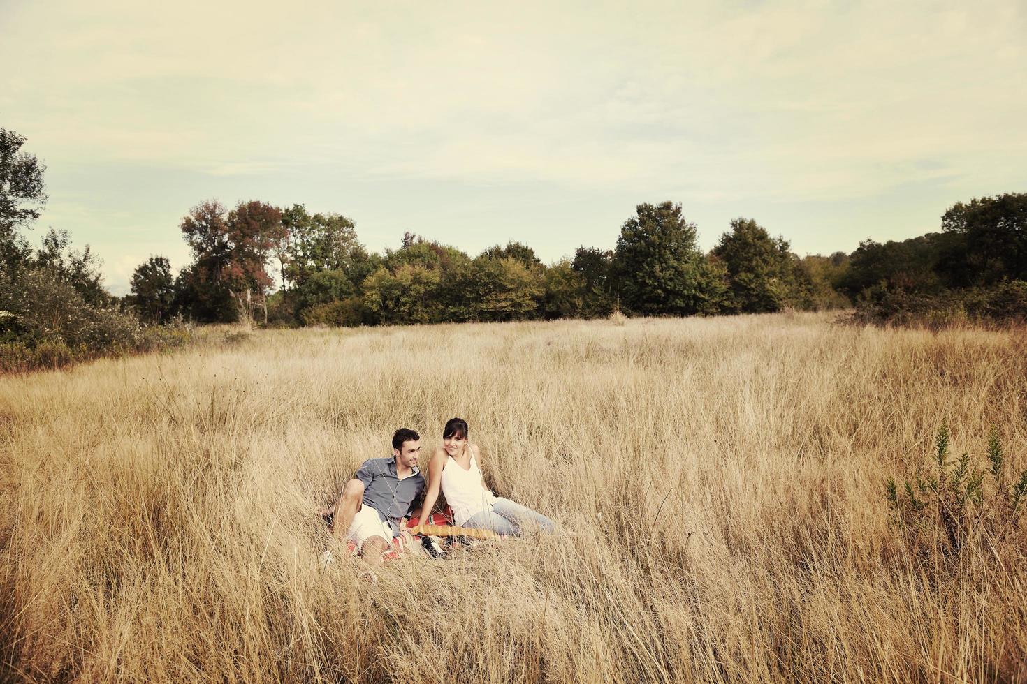 casal feliz desfrutando de piquenique no campo em grama longa foto