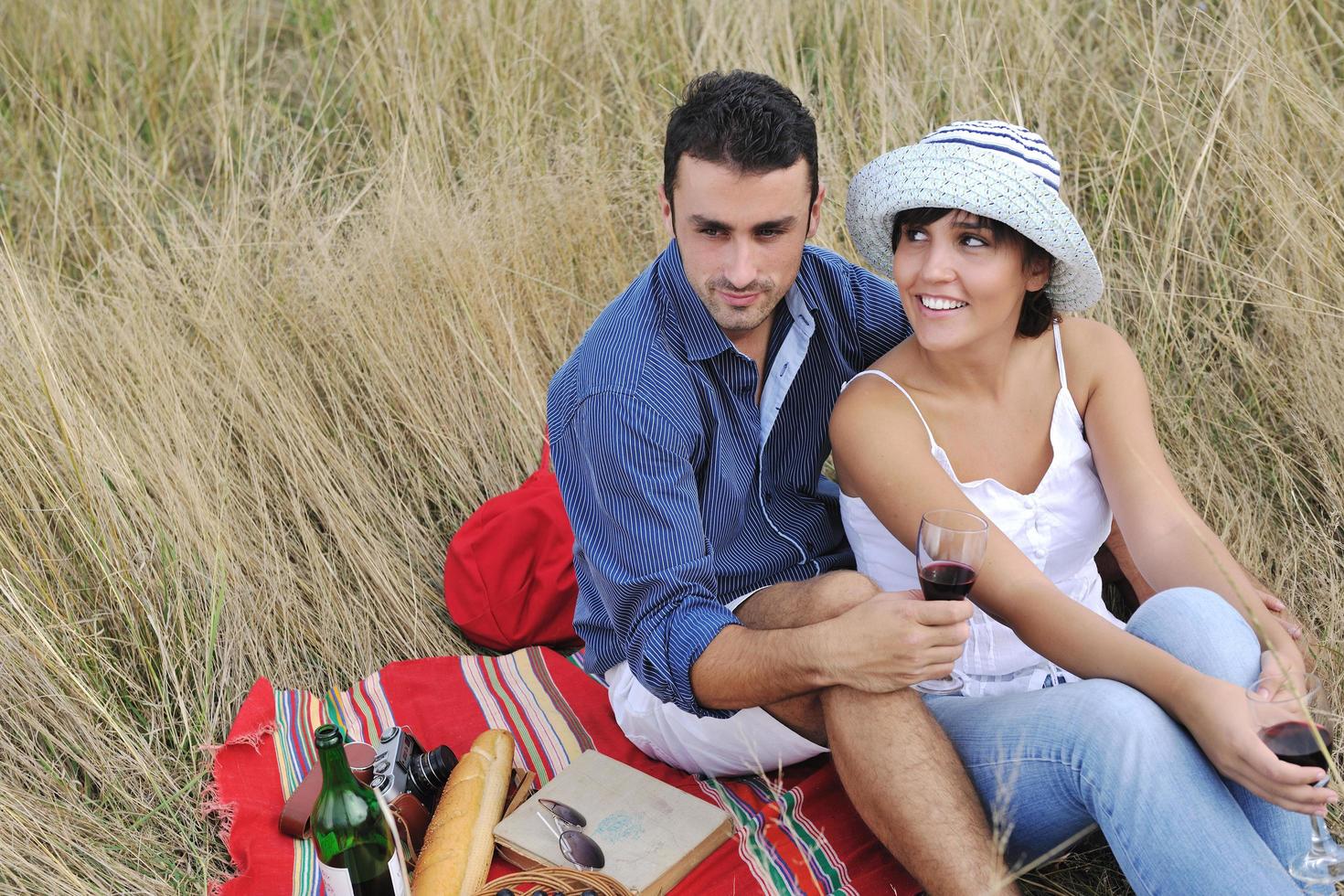 casal feliz desfrutando de piquenique no campo em grama longa foto