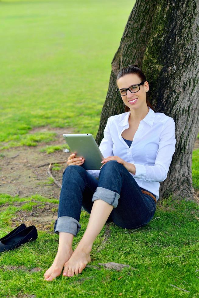 mulher jovem e bonita com tablet no parque foto