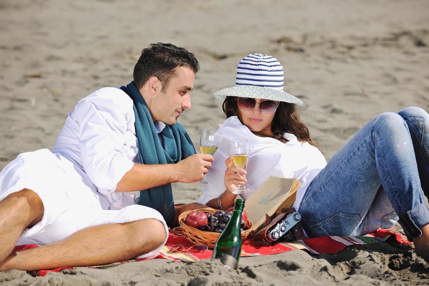 jovem casal desfrutando de piquenique na praia foto